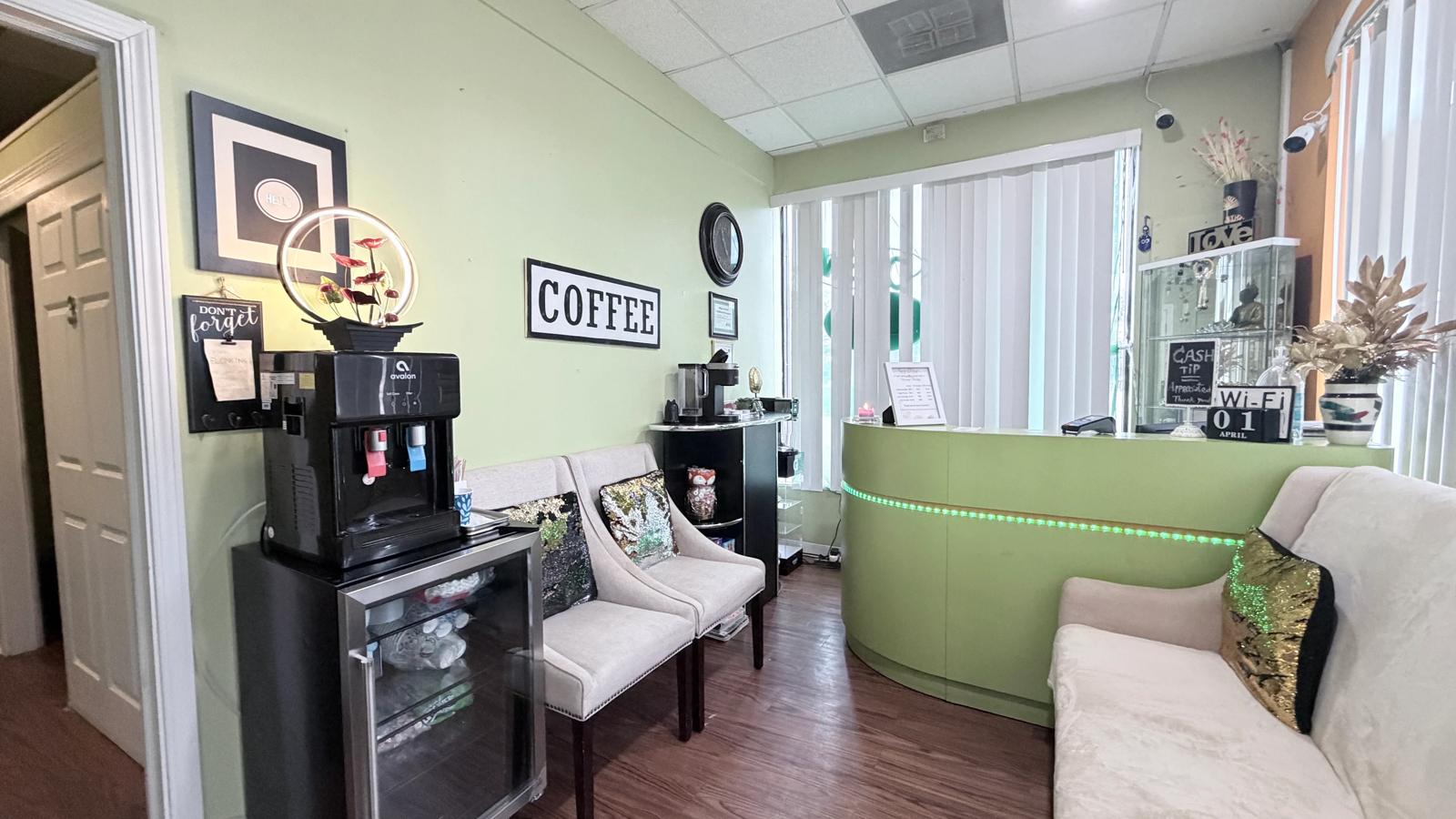 Reception at Sunrise Massage Therapy with the lime-green front desk, cream armchairs and a coffee station